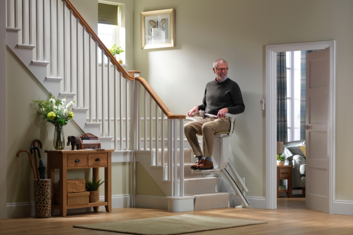 Senior feliz hombre bajando las escaleras en su Stannah