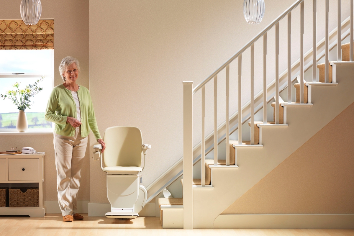 Senior mujer de pie feliz por su escalera Stannah